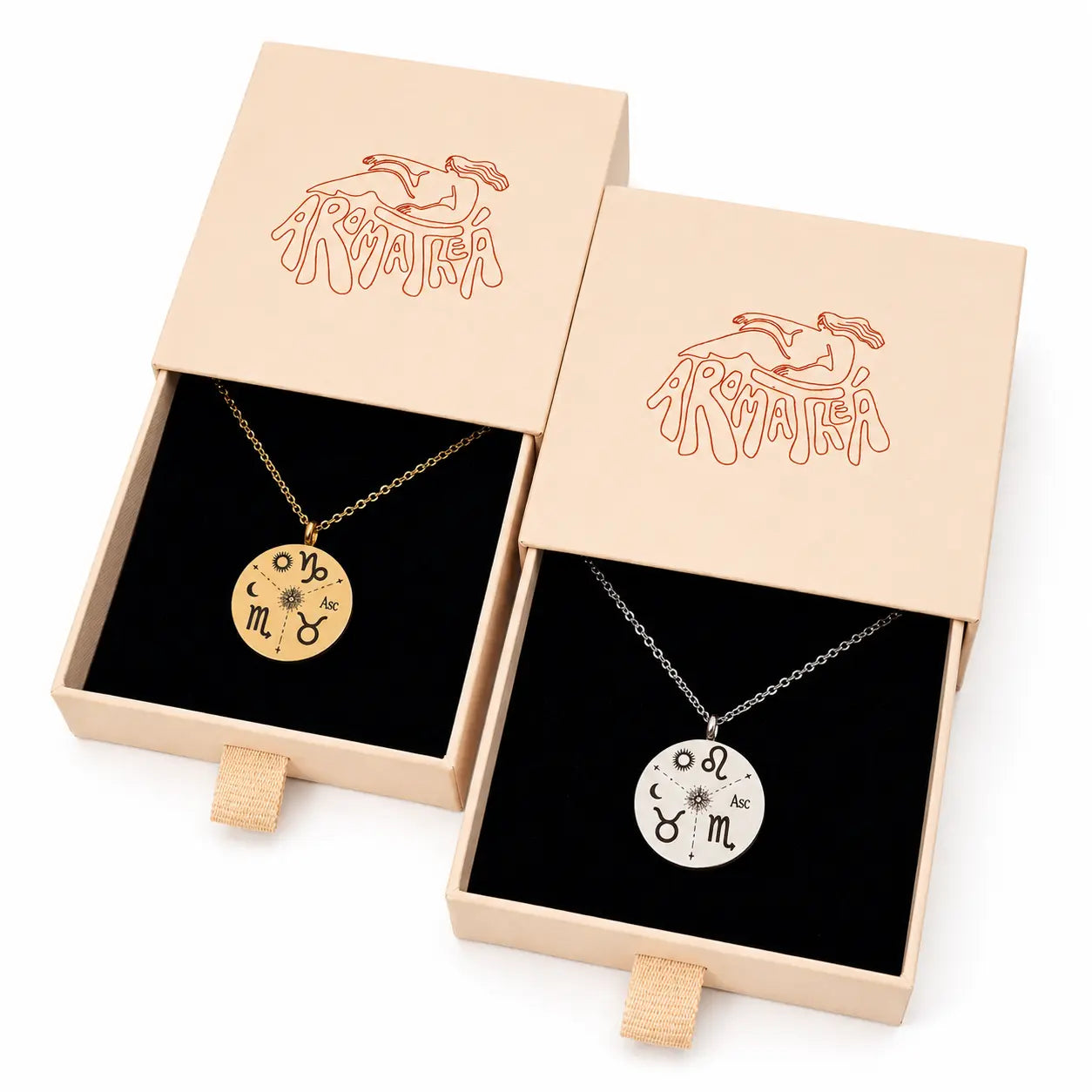 Two open jewelry gift boxes on a white background, each holding a round pendant necklace. The left box contains a gold pendant with zodiac symbols, and the right box contains a silver pendant with zodiac symbols.