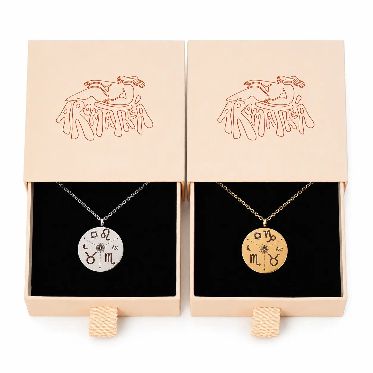 Two Armathea brand necklace gift boxes shown side by side, each containing a round pendant necklace on a black insert. The left box holds a silver pendant with a zodiac symbol, and the right box holds a gold pendant with a zodiac symbol.